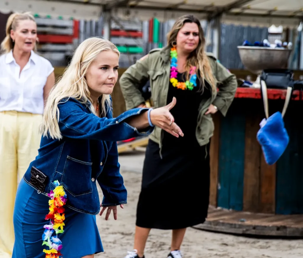 Women play Cornhole at summer party with team building and fun activities
