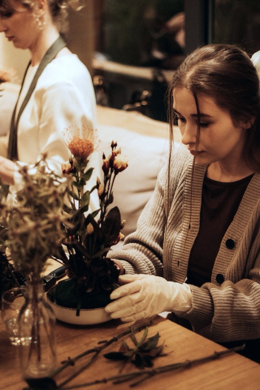 Deltager arbejder koncentreret med sit blomsterarrangement