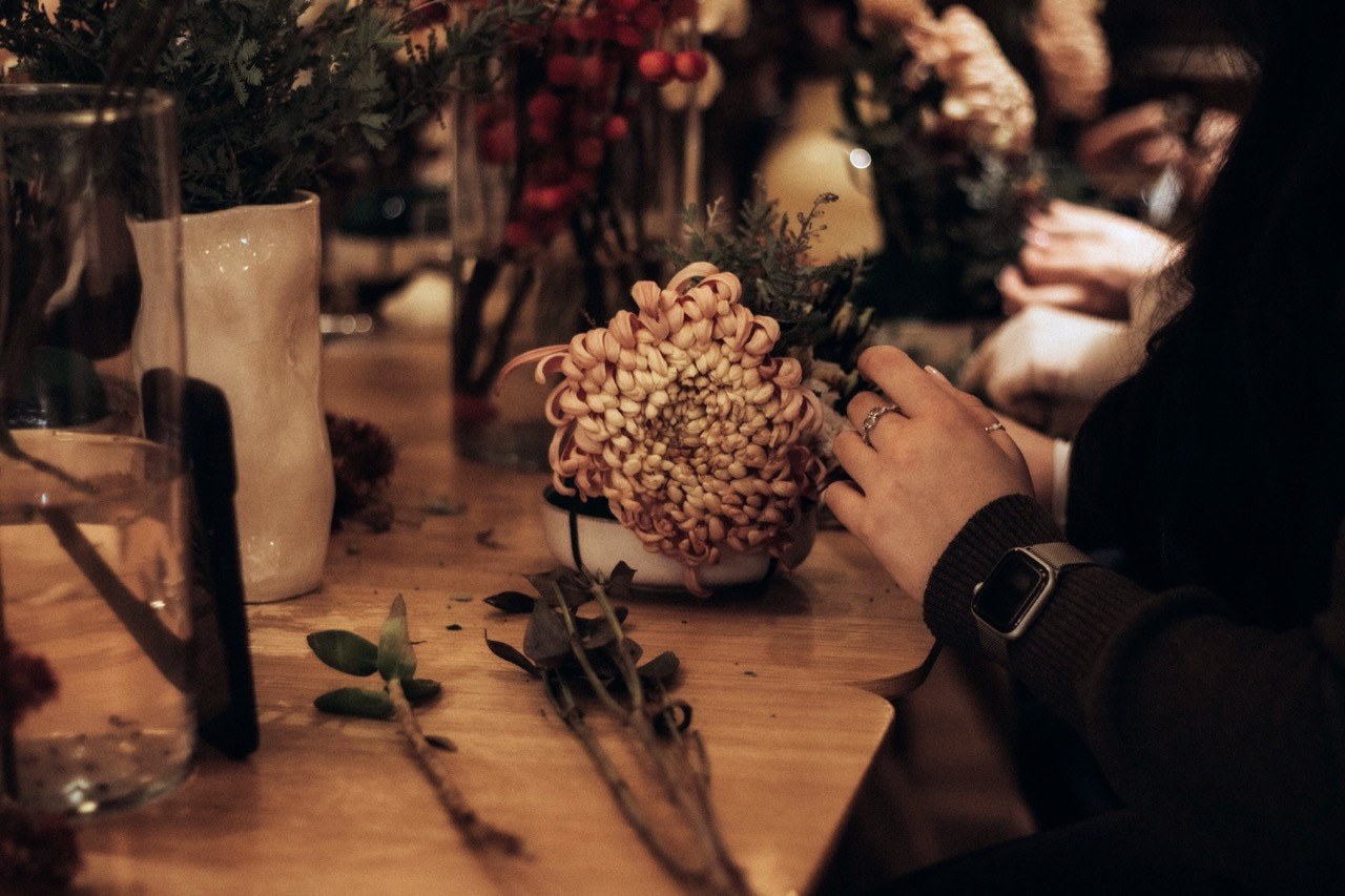 Blomsterbinding ved langbord med blomster, grønt og vaser