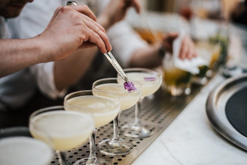 Cocktailkursus, garnering Bartender pynter en række cocktails med blomster
